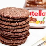 Stack of brown cookies with Nutella jar in background
