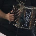Red accordian being played by someone in black shirt