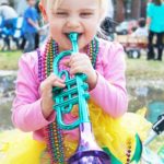 Little girl playing toy trumpet with beads on