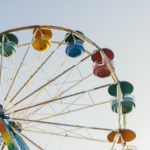 Ferris Wheel with multi-colored cars set against a blue sky.