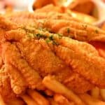Golden brown fried fish on top of french fries