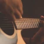 Man playing light brown wood guitar