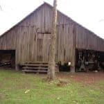 Barn of unpainted wood on green lawn