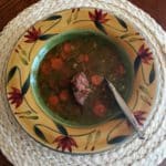 Lentil soup with carrots in beige bowl decorated with red flowers