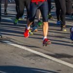 Legs of runners on a gray road