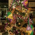 Green Christmas tree trimmed with purple, gold and green ornaments and Mardi Gras beads