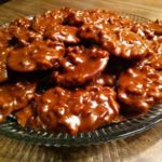 brown pralines with nuts sitting on clear plate on tan table