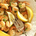 Fried shrimp garnished with lemons on white plate