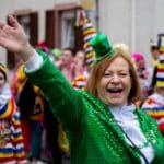 Lady dressed in green with tiny green hat waving