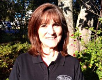 Smiling photo of bookkeeper wearing a black polo shirt with The Stockade logo on the front.